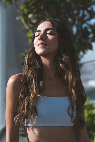 Attractive girl standing outside with eyes closed and face towards the sun
